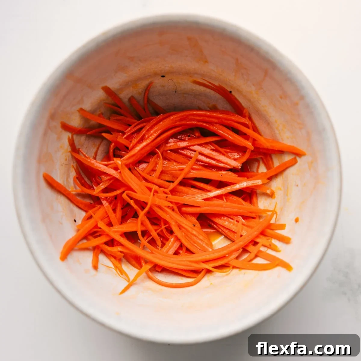 The carrots being shredded and marinated in the dressing for this veggie sandwich.