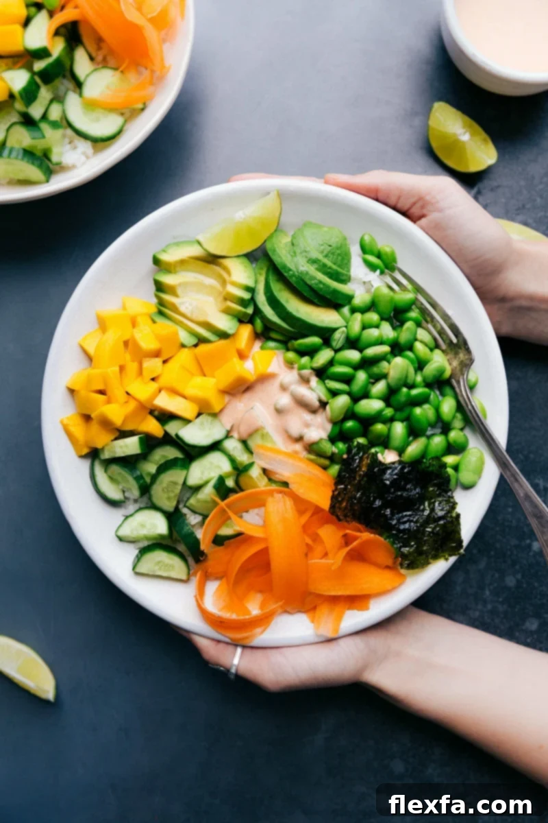 A deconstructed vegetarian sushi bowl with rice, avocado, mango, and edamame.