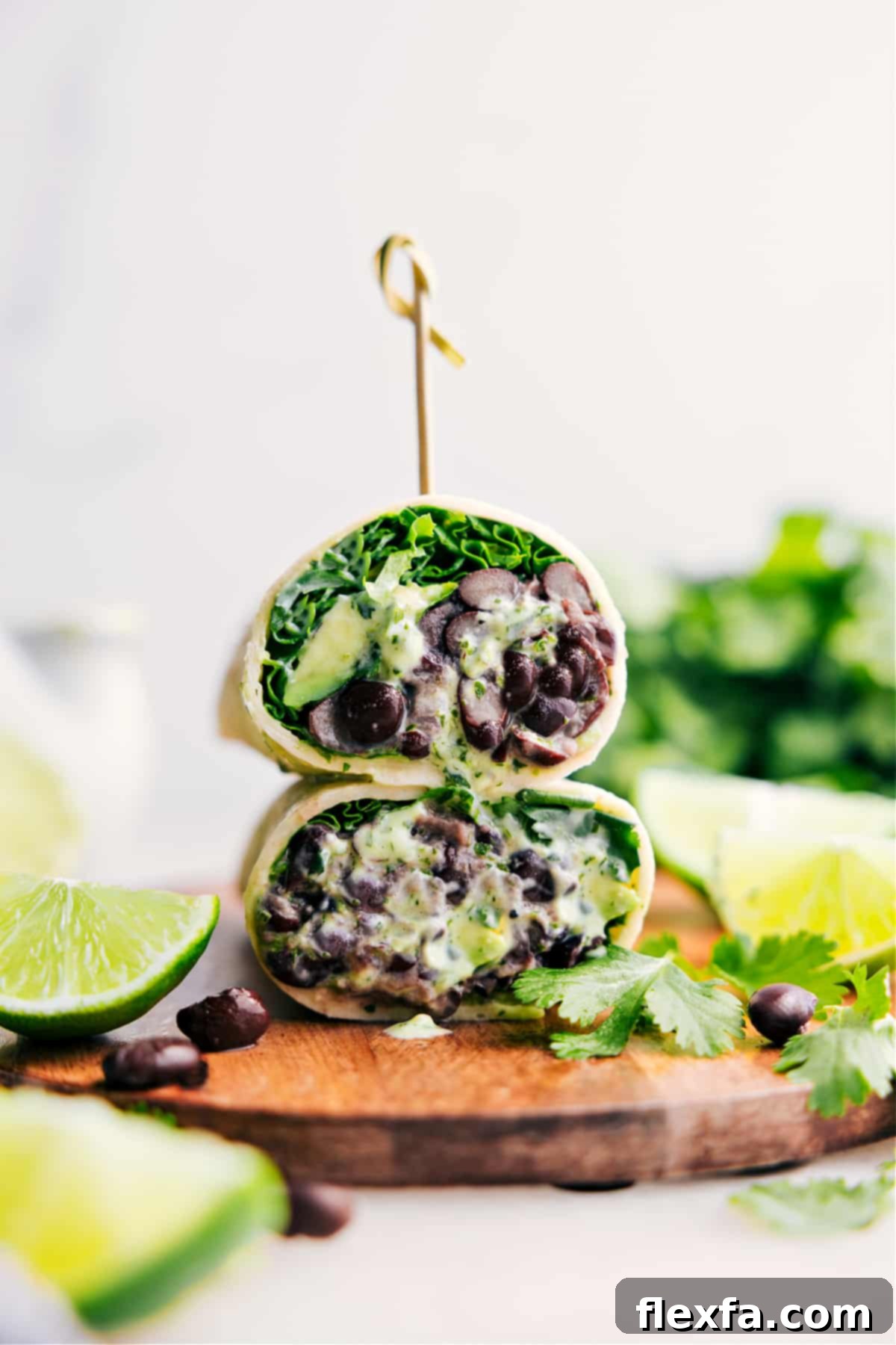 Black bean wraps cut in half and stacked to show the creamy avocado and cilantro-lime dressing inside.