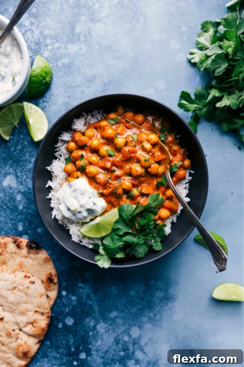 A comforting bowl of creamy chickpea curry garnished with fresh cilantro and a lime wedge.