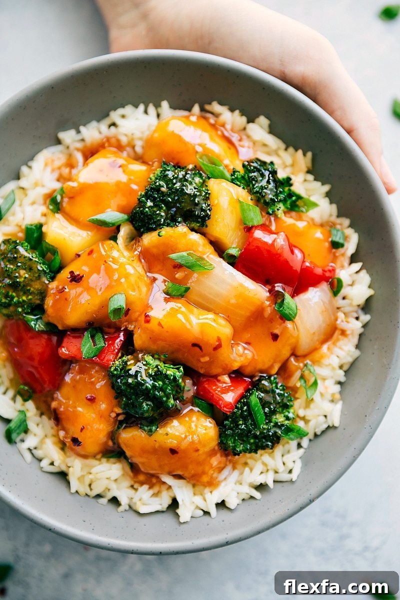 Baked sweet and sour chicken on a bed of rice with fresh green onions on top.
