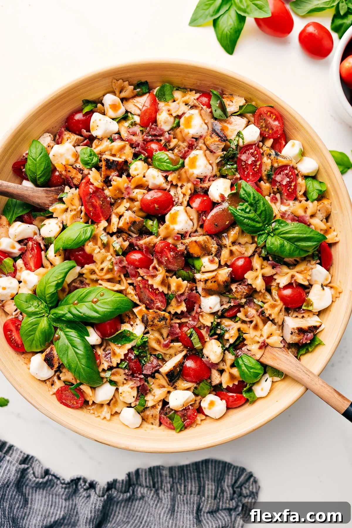 Easy And Delicious Caprese Pasta Salad Ready Caprese Pasta Salad in a large bowl with dressing drizzled over the top, ready to enjoy.
