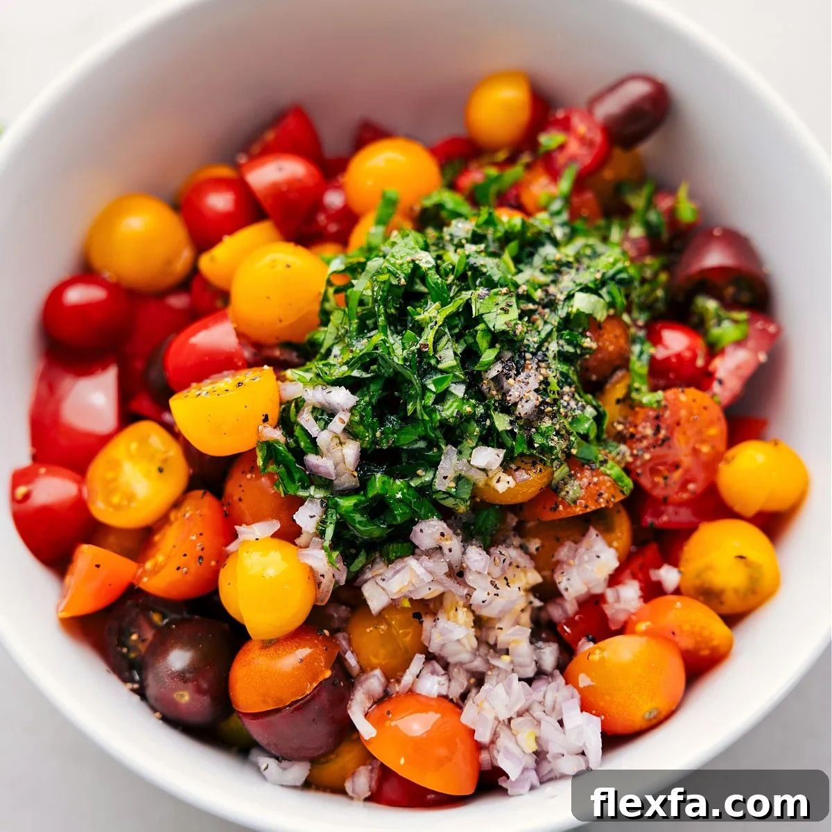 All the ingredients in this cherry tomato salad recipe in a bowl ready to be tossed together.