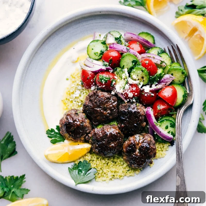 Meatball bowls filled with juicy meatballs, fluffy couscous, cucumber tomato salad, and a creamy lemon herb sauce.