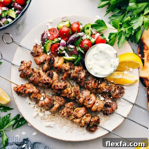 Greek Chicken Bowls on a plate with an easy greek salad, tzatziki dressing, all over rice.