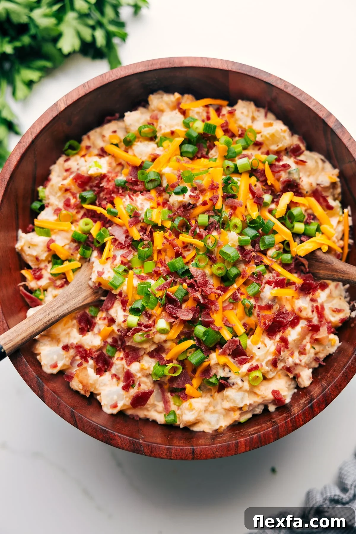 Loaded Potato Salad in a large bowl topped with bacon, cheese, and green onions.