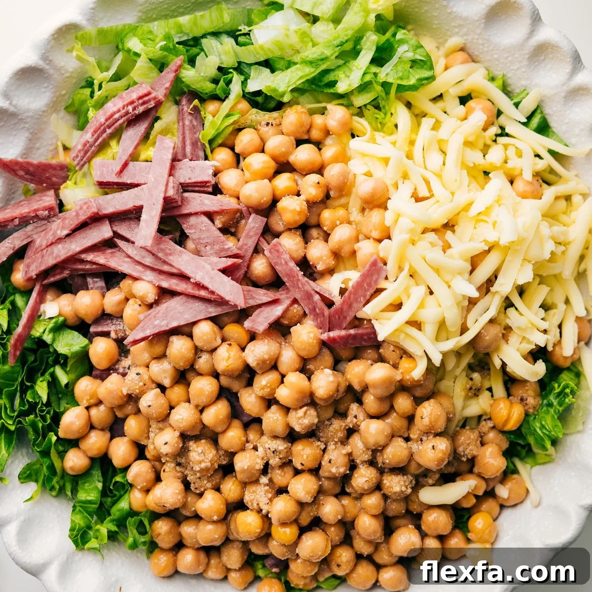 The salad ingredients in a bowl with dressing, ready to be tossed.