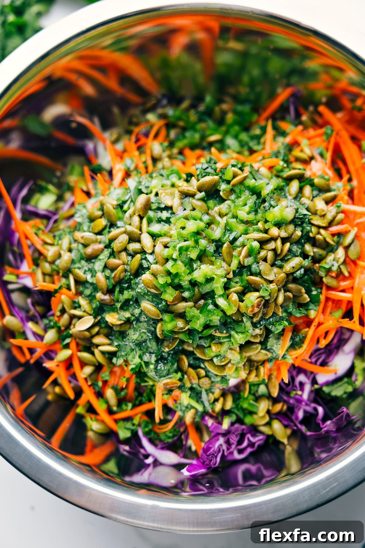 Healthy Slaw ingredients in a large bowl with the dressing poured over the top, ready to be tossed together.