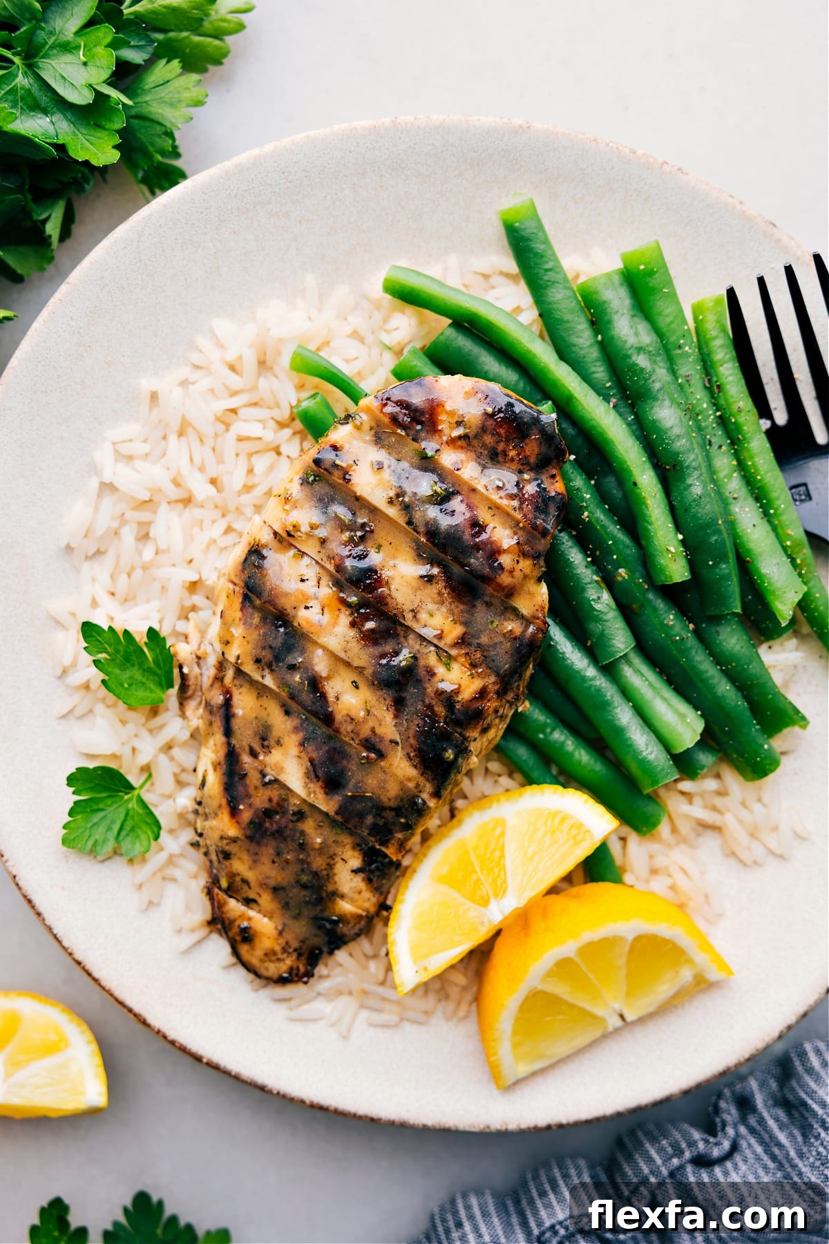 Italian Chicken Marinade recipe on a plate over a bed of rice with green beans.