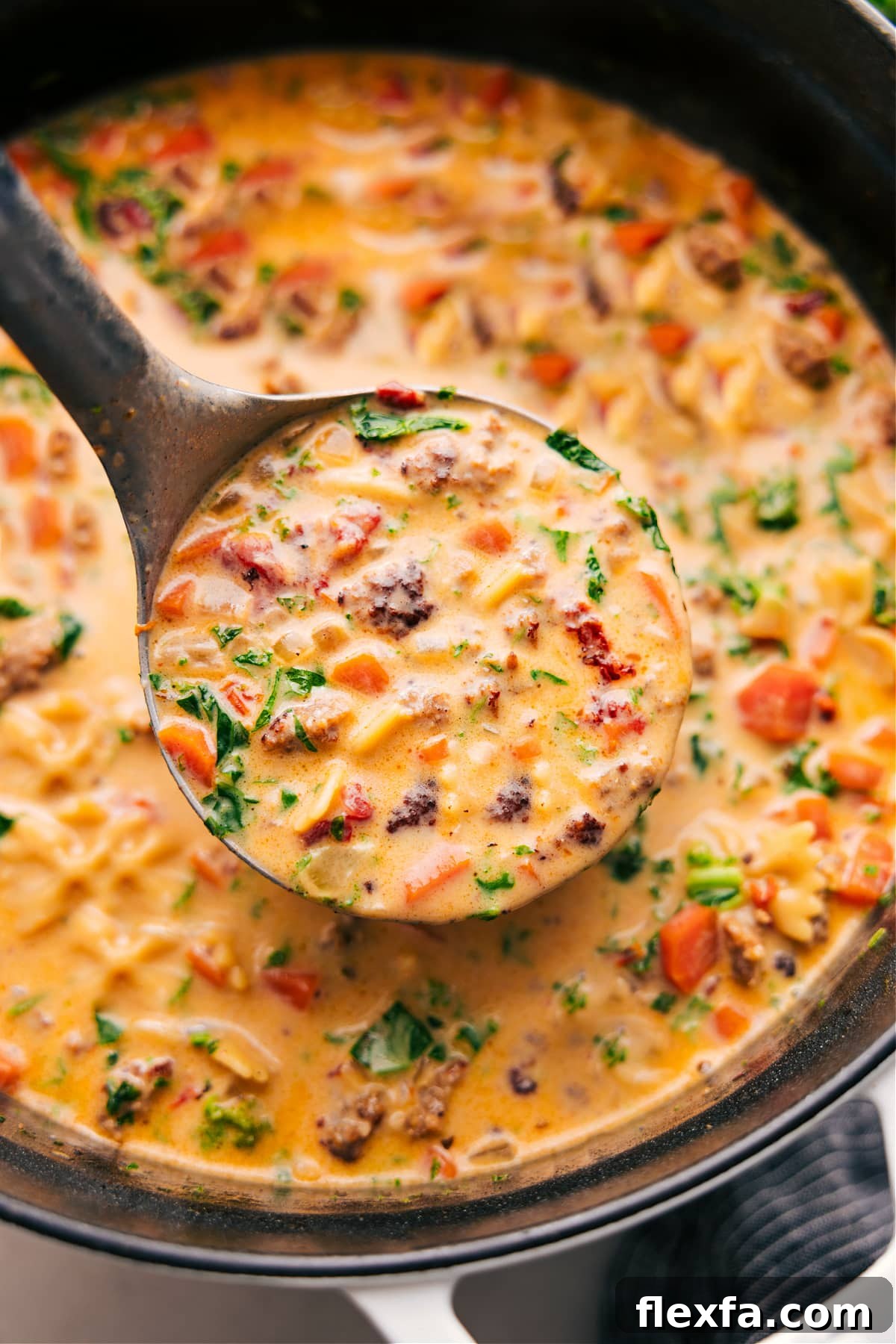 Sausage pasta soup with vegetables, sun-dried tomatoes, pasta, and creamy broth.