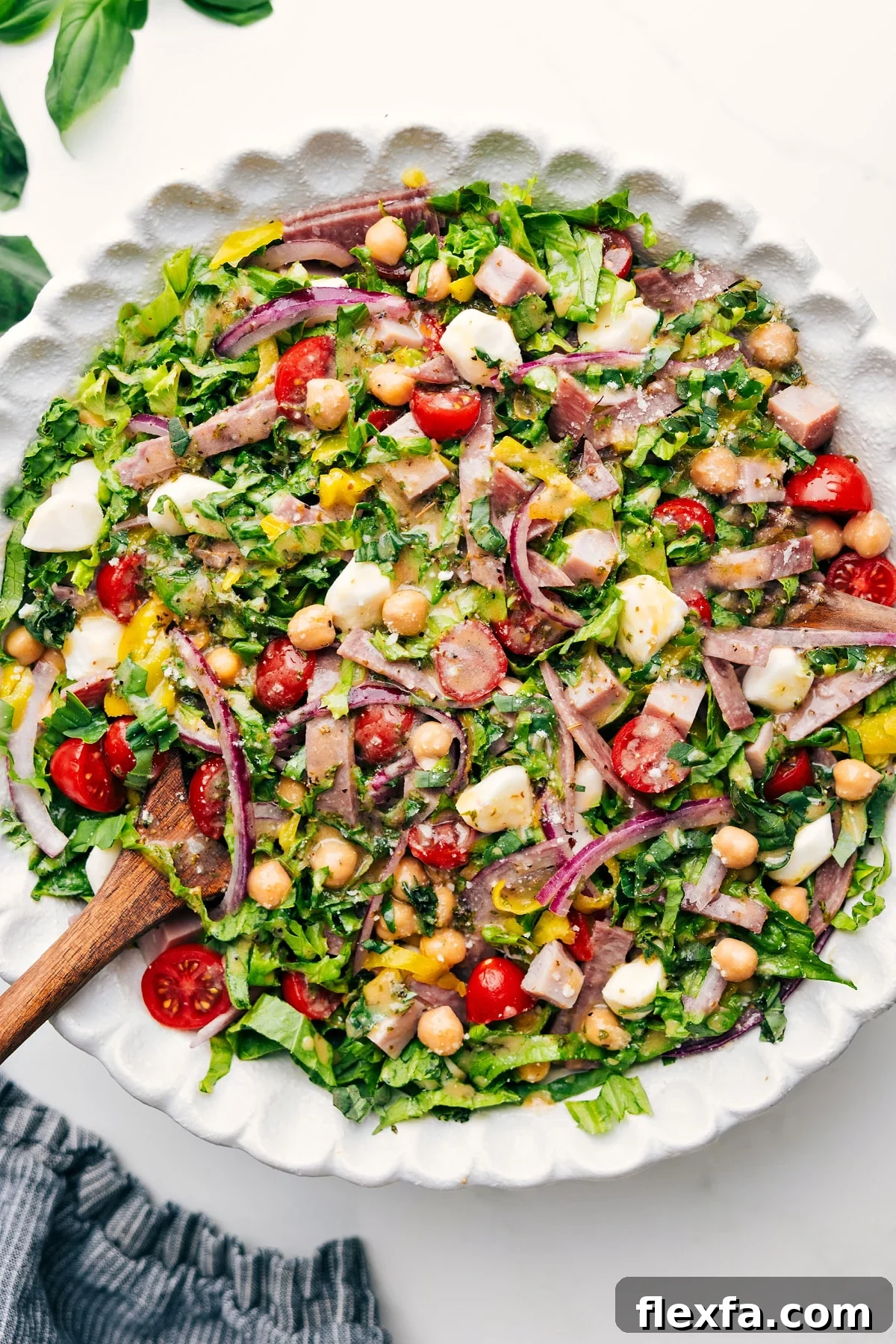 Fresh chopped salad loaded with salami, ham, chickpeas, mozzarella, pepperoncini, basil, and lemon dressing.