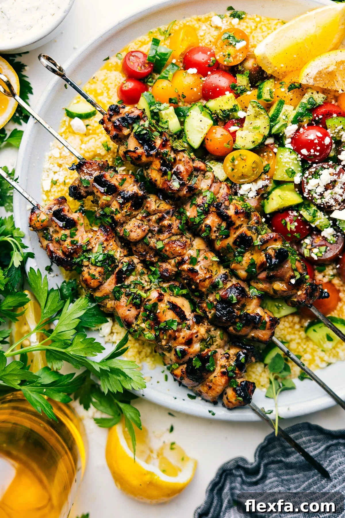 Chicken Souvlaki served over couscous with a cucumber tomato salad on the side.