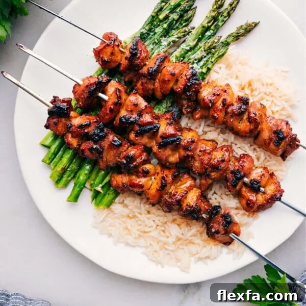 Baked Chicken Bites on skewers over rice and asparagus.