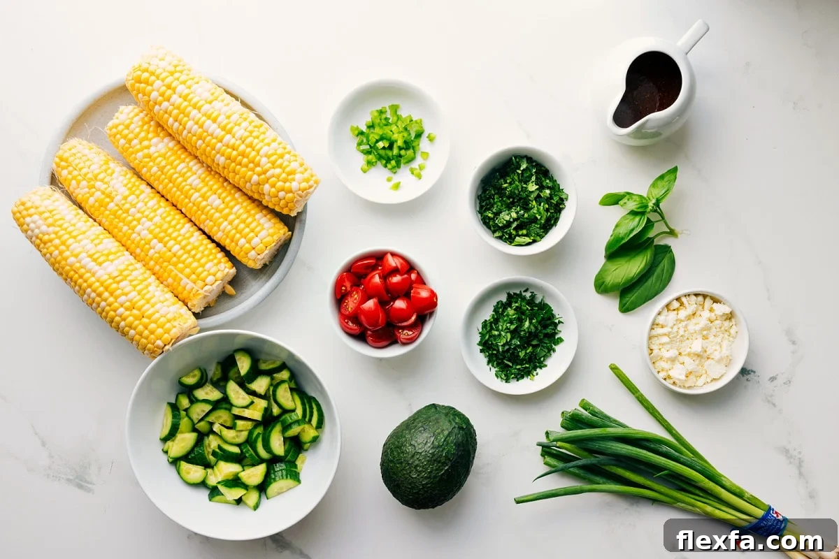 All the ingredients in this recipe prepped out for easy assembly including the corn, cucumbers, avocado, tomatoes, jalapeños, cilantro, parsley, basil, green onions, feta, and vinaigrette.