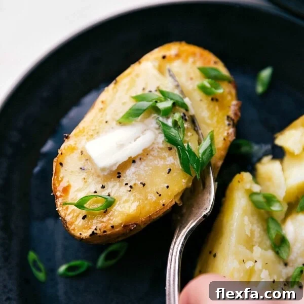 Freshly baked potatoes topped with melting butter and sprinkled with vibrant green chives, ready to be eaten.