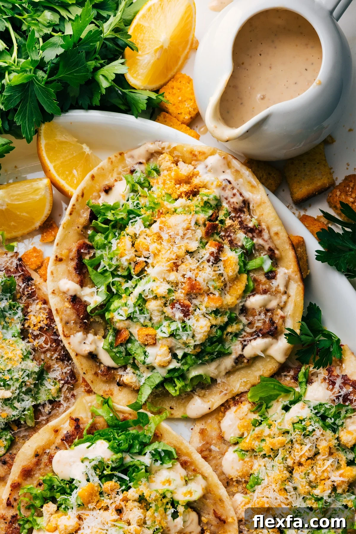 Chicken Caesar Smashed Tacos on a plate with fresh lemon wedges, extra Caesar dressing, and croutons on the side.