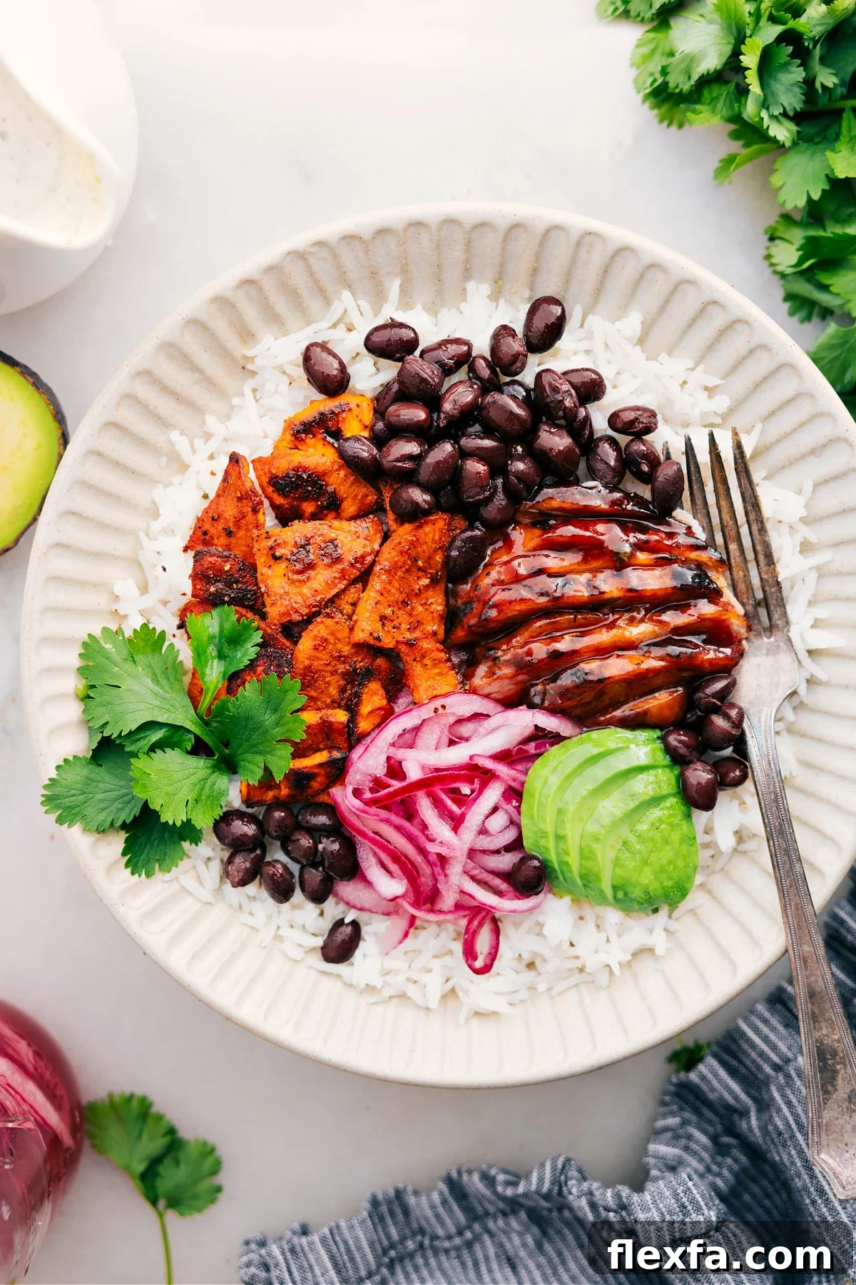 BBQ chicken bowl with sweet potatoes, avocado, rice, and pickled onions