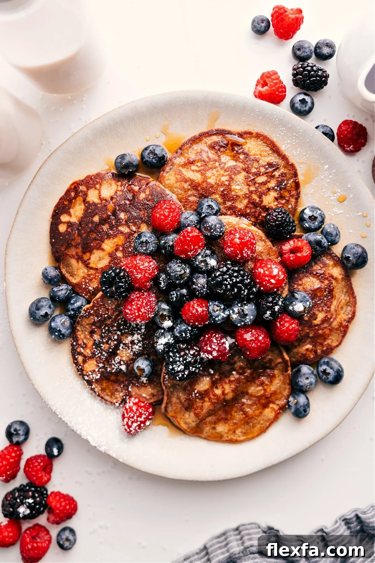 Fluffy healthy pancakes with golden edges served with fresh berries and maple syrup.
