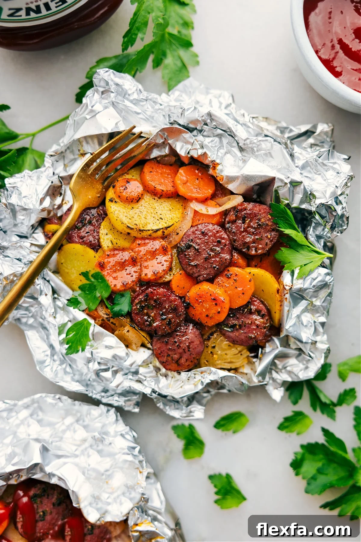 Foil packets filled with sausage, thinly sliced potatoes, carrots, and onions.