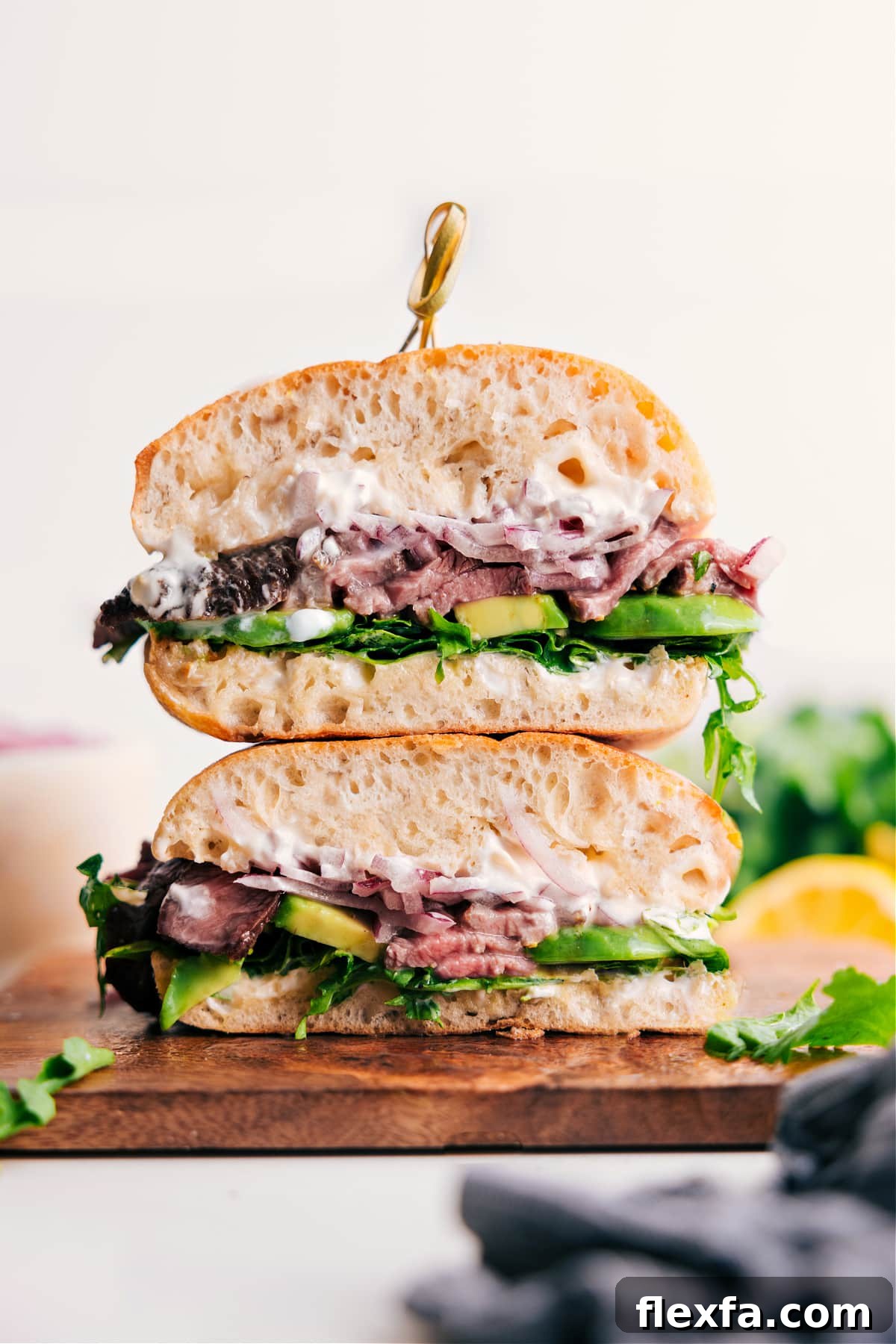 Steak sandwich recipes with sliced steak, avocado, arugula, pickled onions, and lemon aioli.