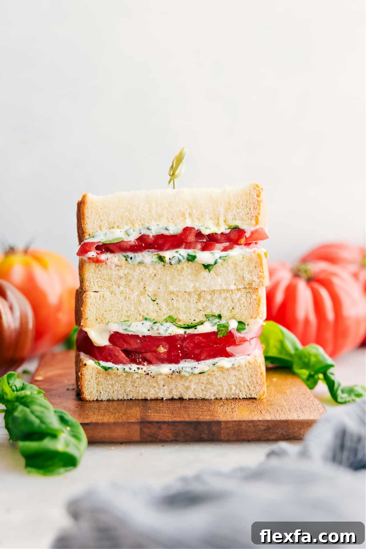 Tomato sandwich with thick tomatoes and basil mayo on soft white bread.