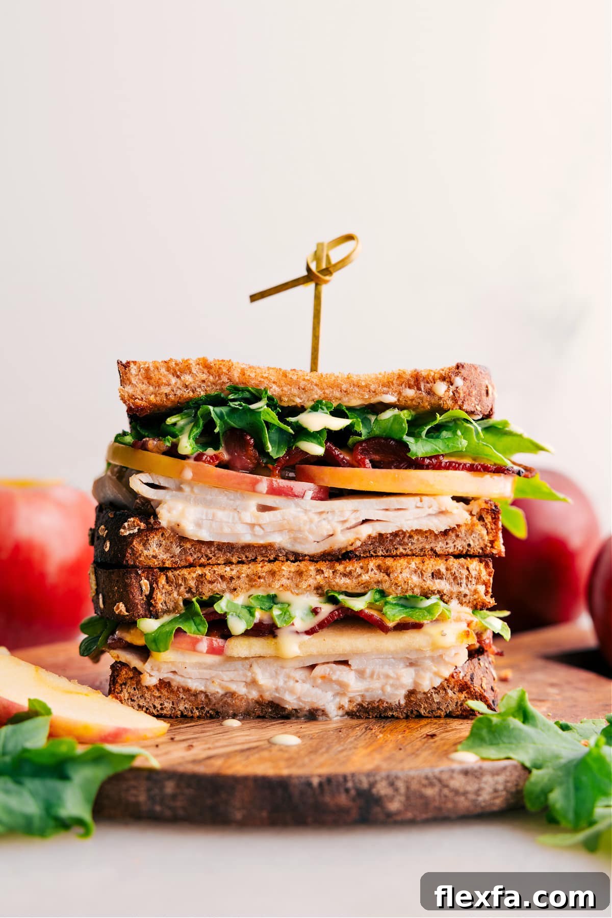 Turkey sandwich with sliced turkey, apple, bacon, Gouda, and dressed greens on toasted bread.
