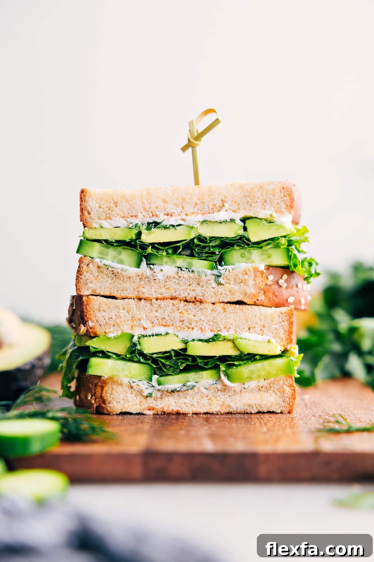 Avocado sandwich with cucumber and creamy herb spread on hearty bread.