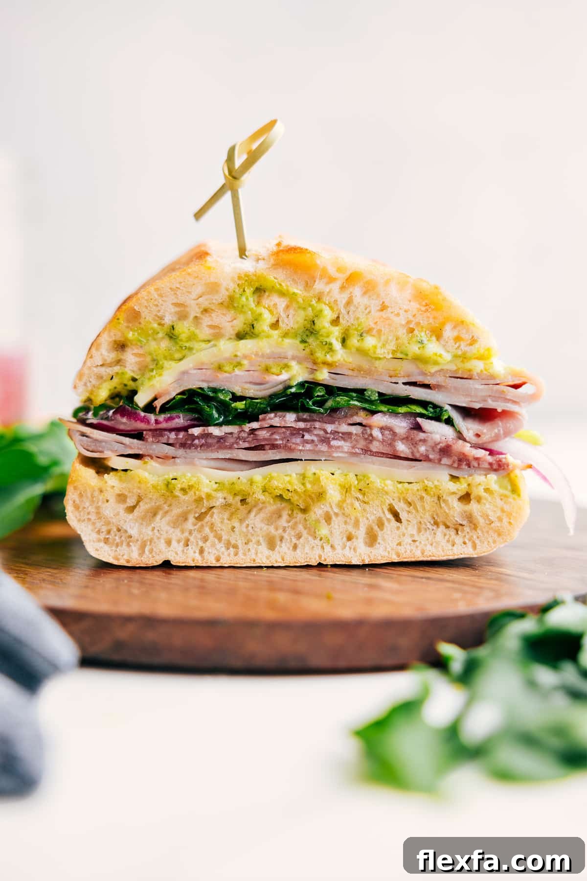 Ciabatta sandwich stacked with deli meats, provolone, pickled onions, and dressed greens.
