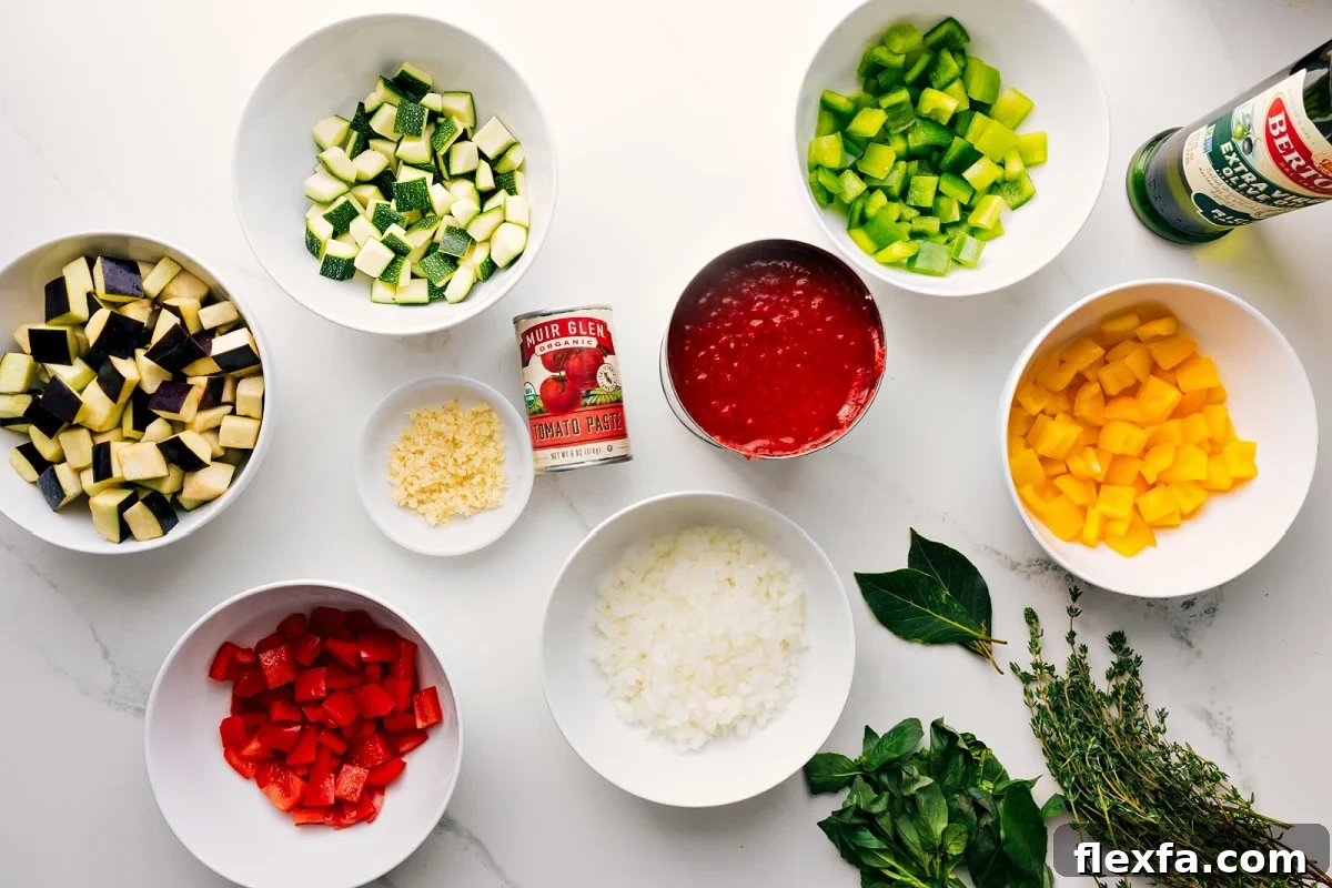 All the ingredients in this recipe prepped out for easy assembly including the veggies, tomatoes, oil, garlic, tomato paste, and fresh herbs.
