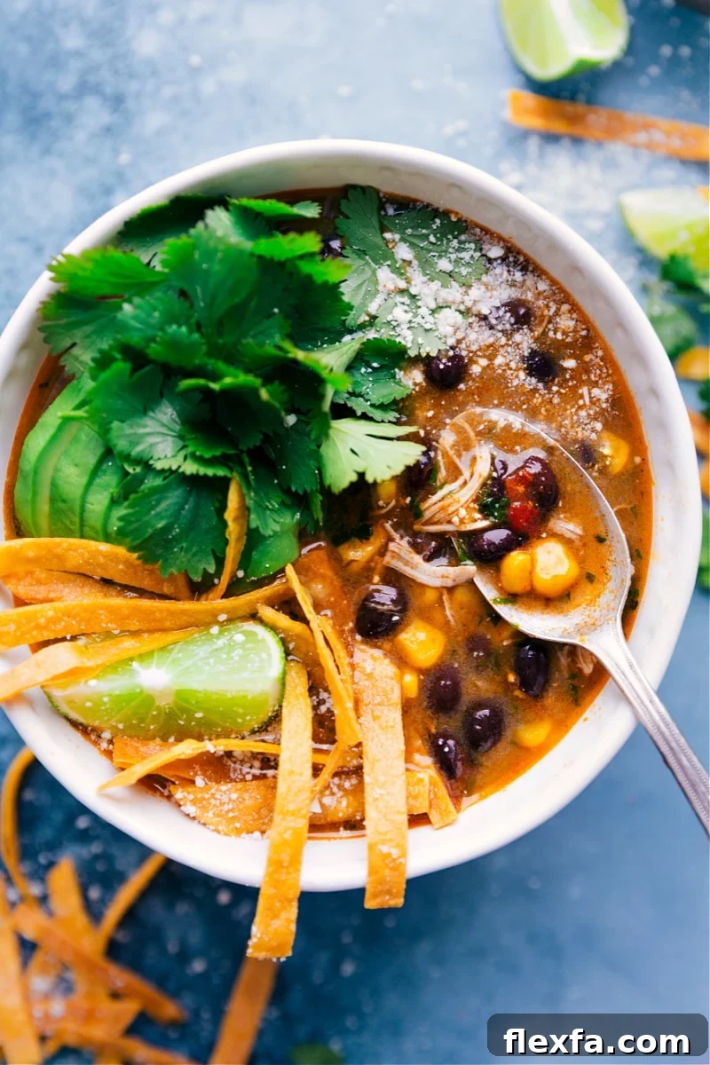 Crockpot salsa verde chicken soup with shredded chicken, beans, corn, and salsa verde.
