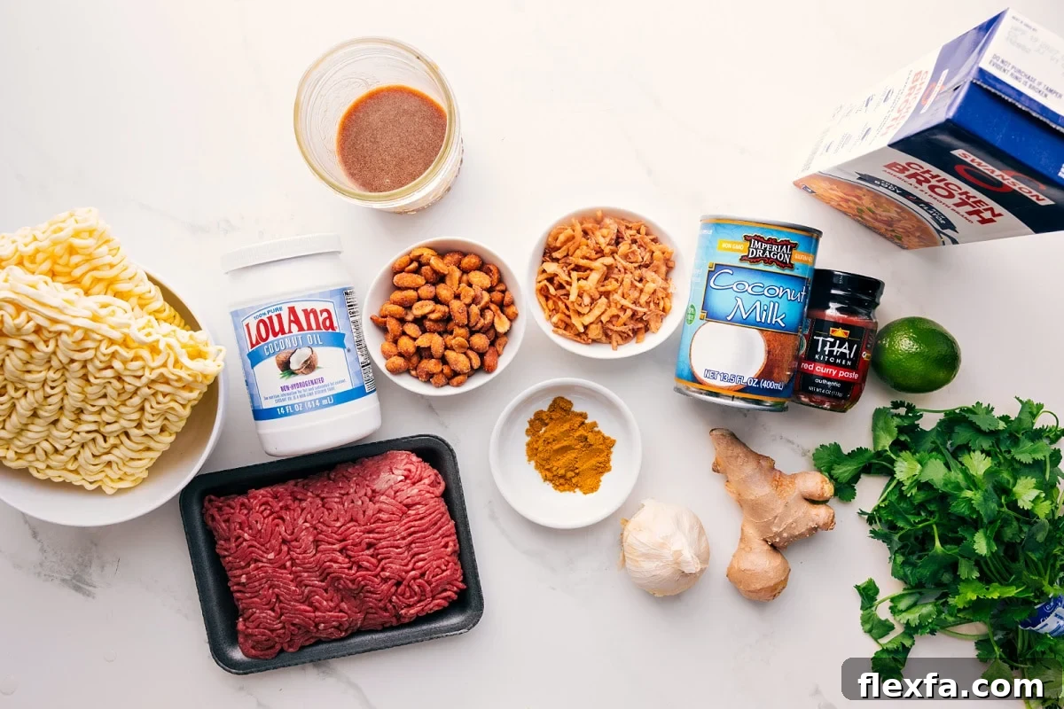All the ingredients in this recipe prepped out for easy assembly including the ramen, oil, beef, peanuts, sauce, fried onions, seasonings, garlic, ginger, coconut milk, red curry paste, lime, broth, and cilantro.
