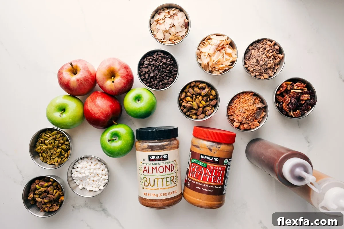 All the ingredients in this recipe prepped out for easy assembly including apples, pepitas, marshmallows, nuts, granola, chocolate, toffee bits, butterfingers, almond butter, peanut butter, chocolate, and caramel.