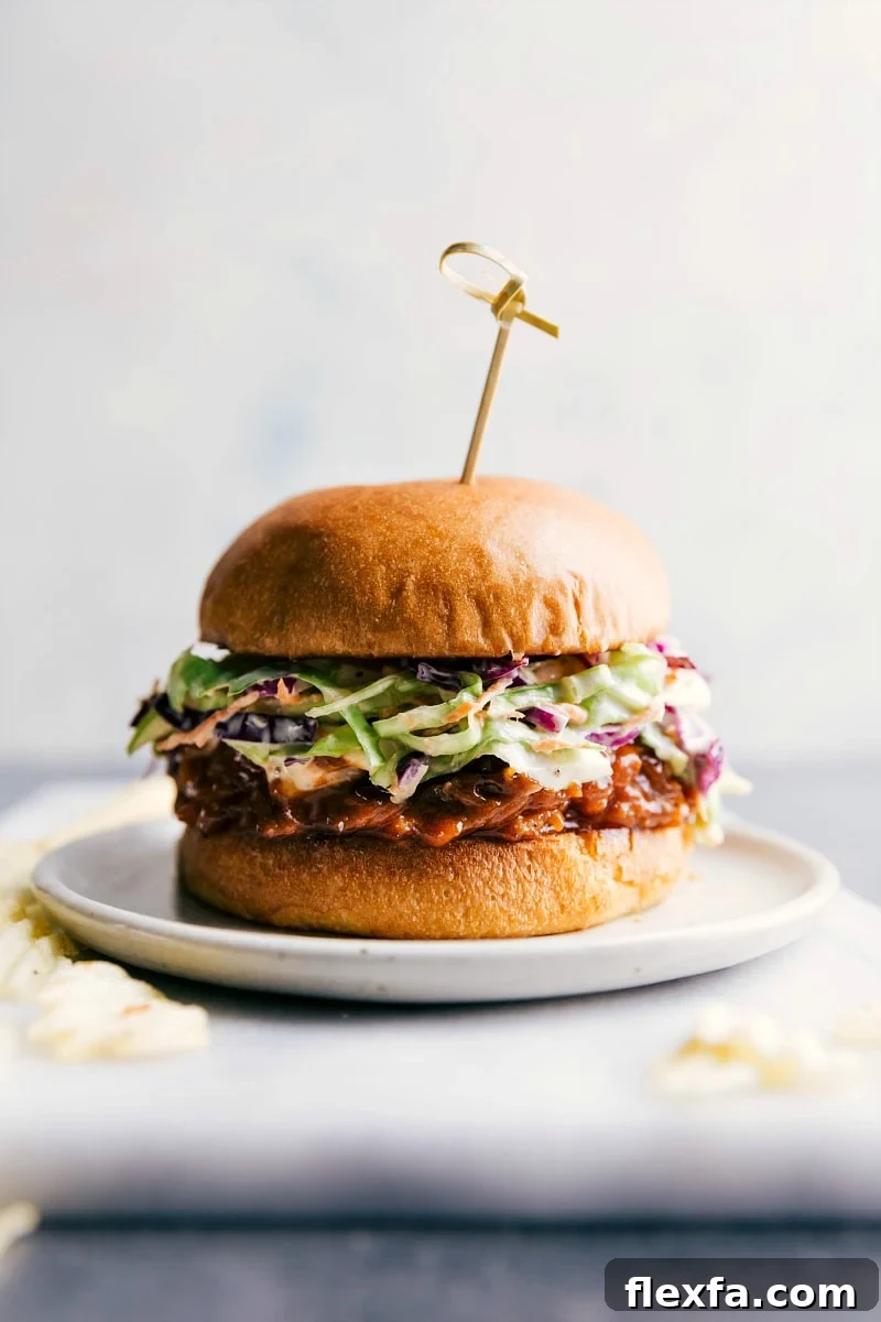 Crockpot BBQ pulled pork sandwich on a plate, overflowing with delicious ingredients, ready to be enjoyed.