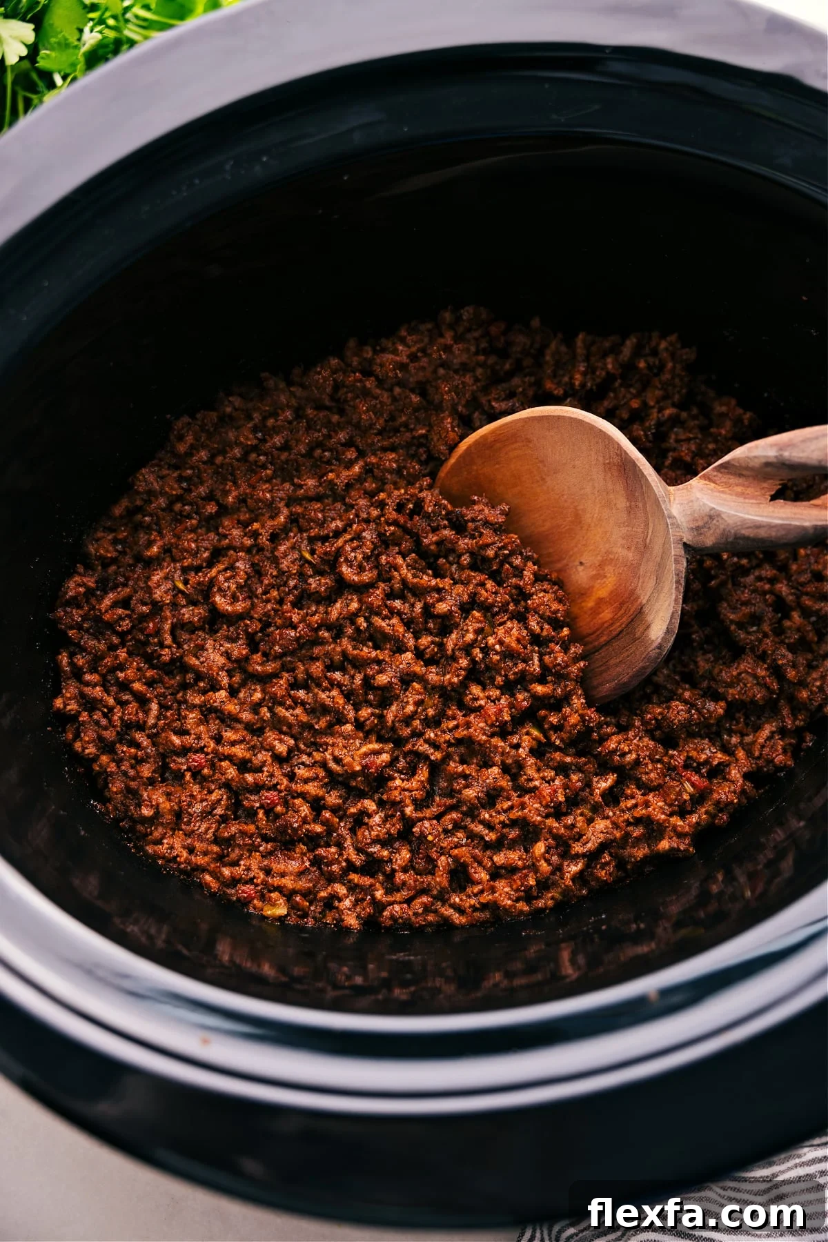 Crockpot taco meat in the slow cooker with a spoonful coming out.