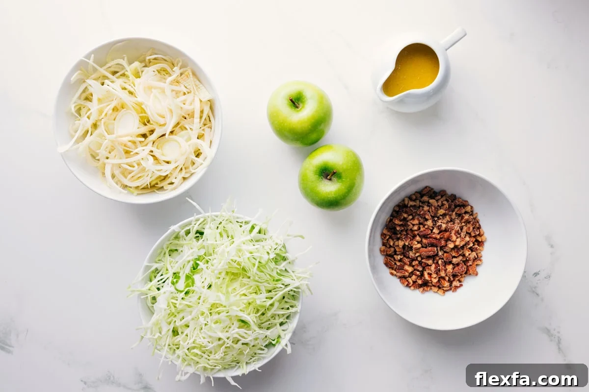 All the ingredients in this recipe prepped out for easy assembly including the apples, cabbage, pecans, and dressing.