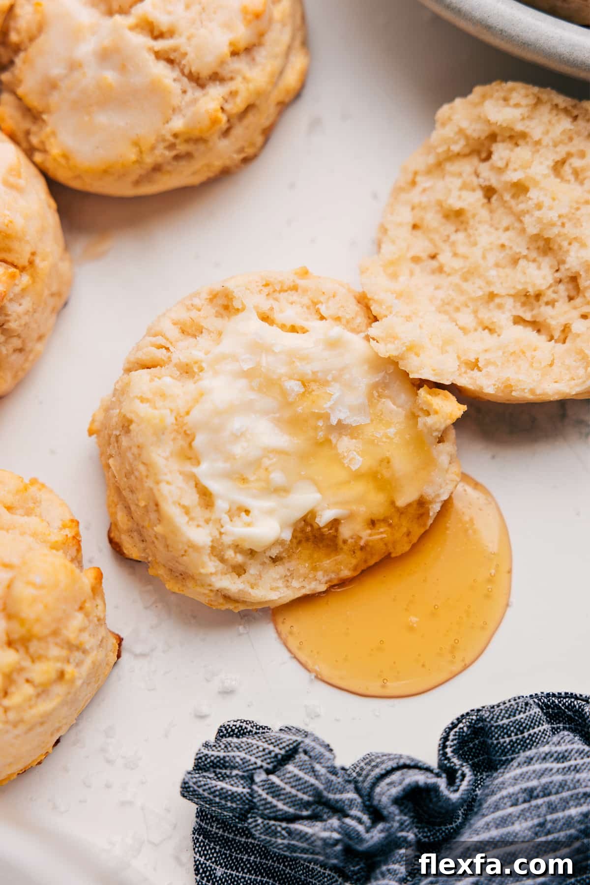 How to Make Fluffy Southern Drop Biscuits 2 Drop Biscuit Recipe topped with butter and drizzled with honey.